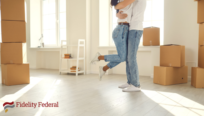 New homeowners hugging in their new home surrounded by moving boxes.